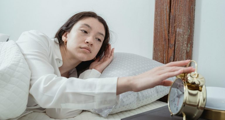 Young woman waking up with alarm clock